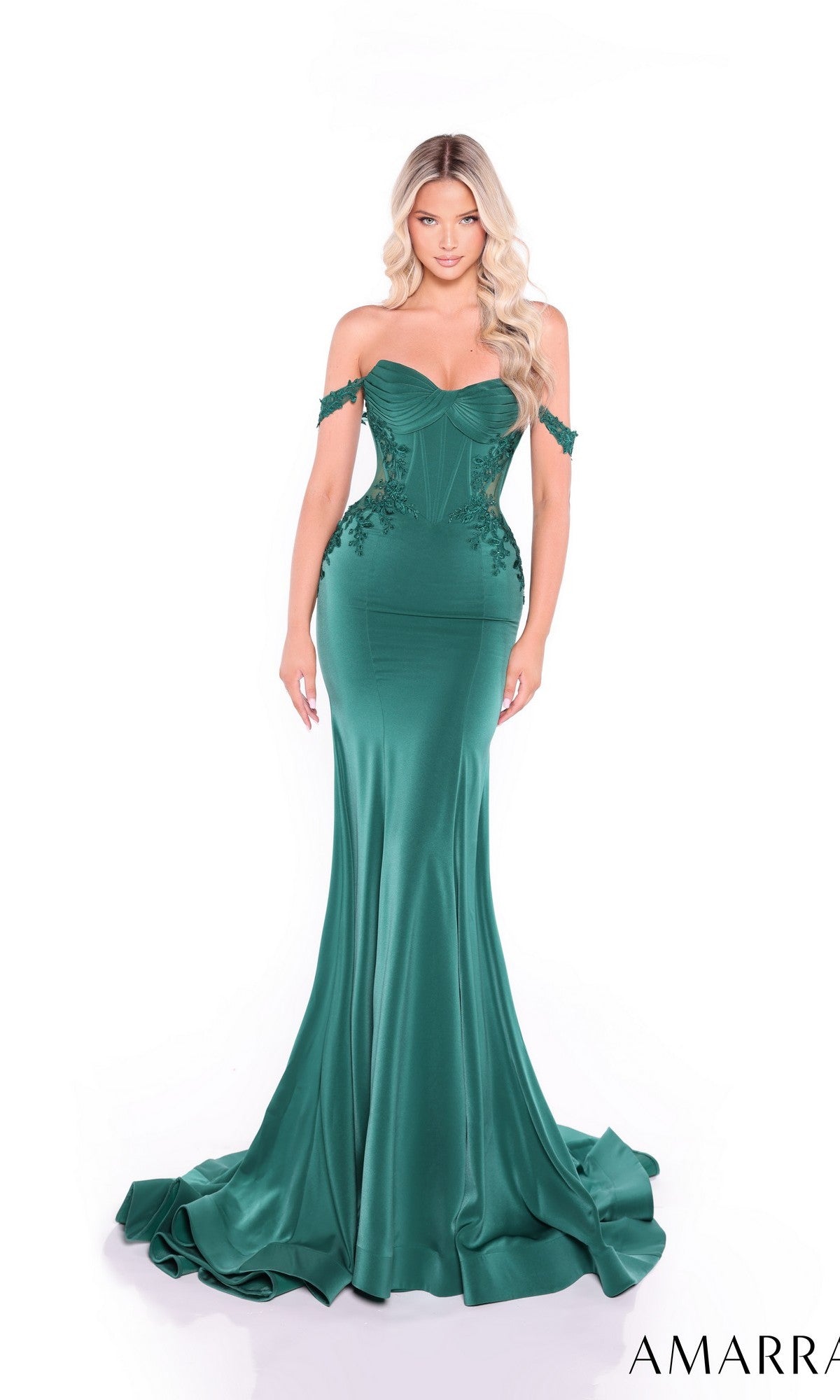 A woman stands against a white background wearing the Amarra 89431, a fitted emerald green off-the-shoulder long prom dress with a corset bodice, floral detailing, and a flared train.